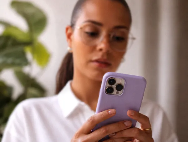 Mulher de óculos olhando para um celular.